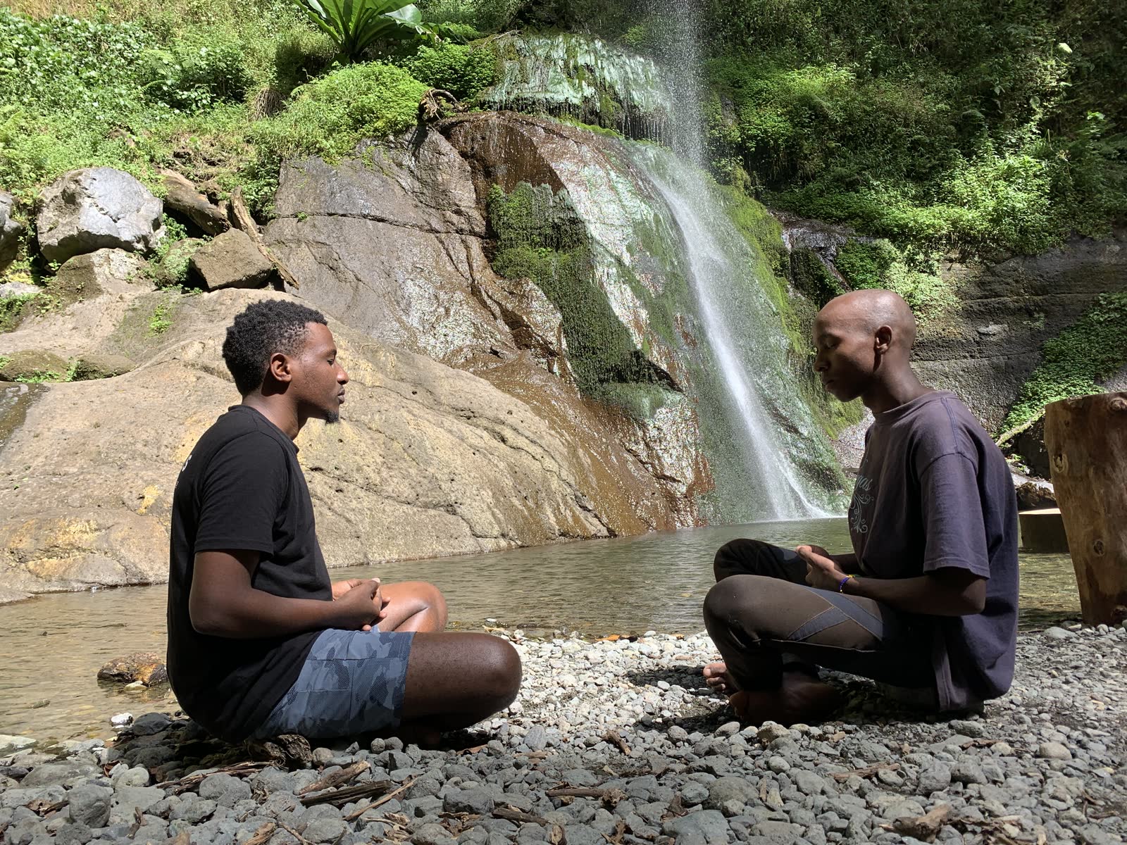 Two people seated facing each other beside a waterfall