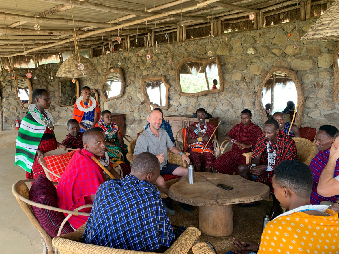 Maasai elders and retreat guests in conversation in the lodge lounge